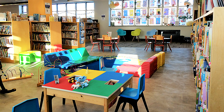 Children's department in Cornwall Public Library with colorful tables, mats, and activity areas