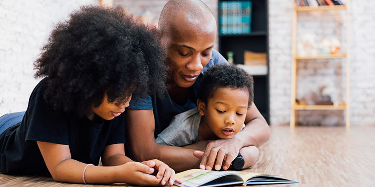 Father and two children reading a book together